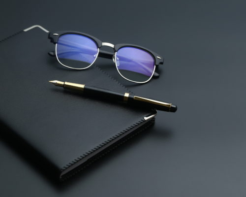 gafas golden pen,notebook,calculator and glasses on black desk